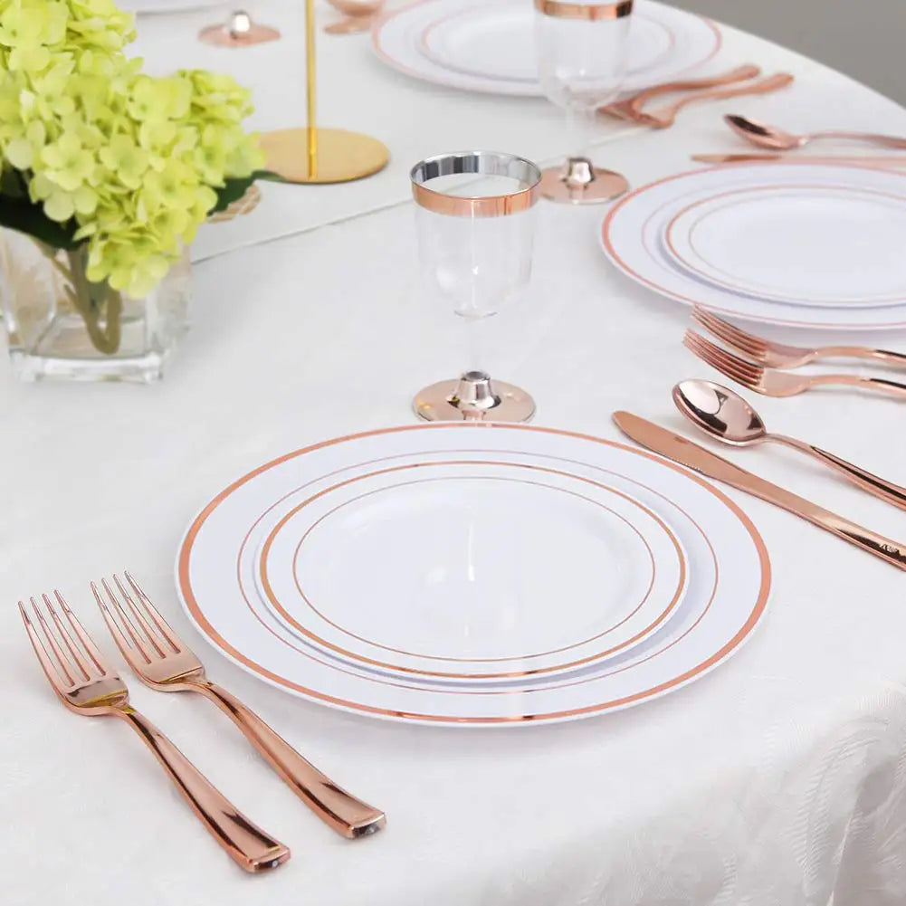Elegante goldrandige Plastik-Essgeschirr-Set auf weißem Tisch mit Besteck und Gläsern