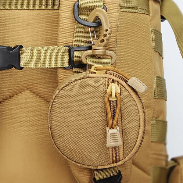 A close-up of a tan nylon pouch attached to a beige strap on a bag, featuring a zipper and a carabiner clip.