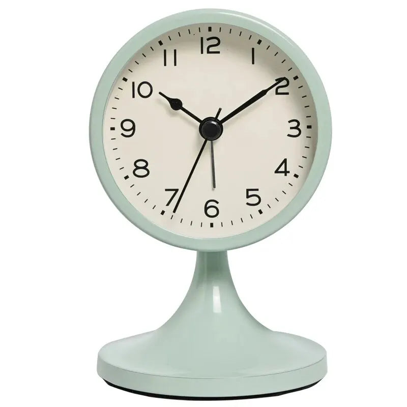 A light mint green round analog alarm clock with a black center and a white face sits on a matching base.