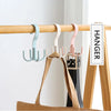 A set of wooden hangers with various colored plastic and metal hooks displayed on a wooden rack.
