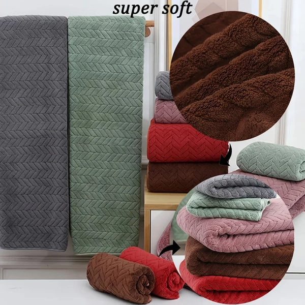 A stack of super soft coral velvet bath towels in various shades of pink, red, and brown.