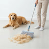 A person is using a long handle broom to sweep loose dog hair across a floor.