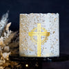 A cylindrical white cake decorated with gold acrylic cross toppers and dried floral accents.