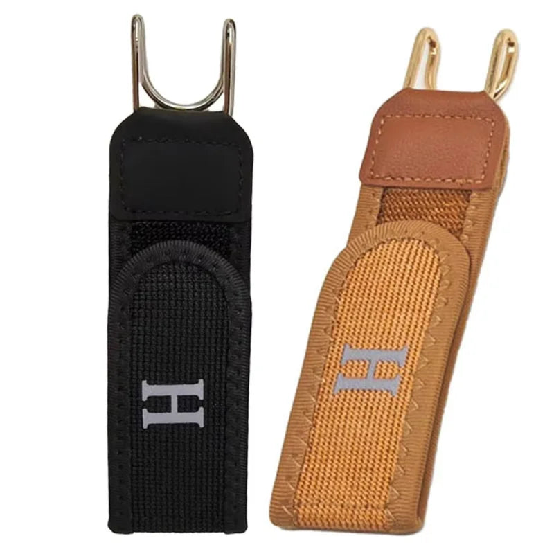 A black adjustable buckleless belt with a tan leather strap and gold-colored hardware.