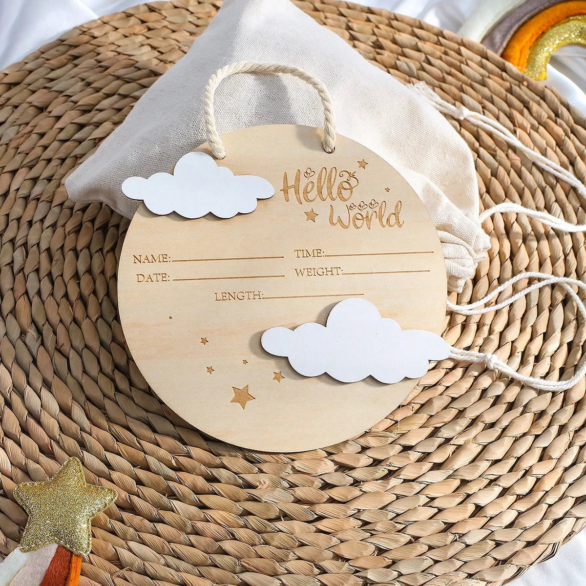 Atrezzo de fotos de recién nacido de madera con recorte de nube y texto 'Hello World' atado con cuerda, sobre una estera teji