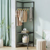 A dark metal coat rack with multiple hanging rods displaying beige and cream coats against a light green wall.