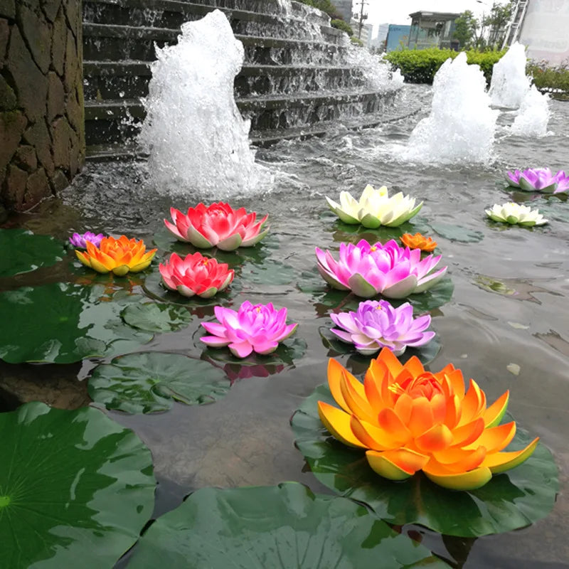 Colorful artificial lotus flowers floating on water with a backdrop of a tiered stone waterfall
