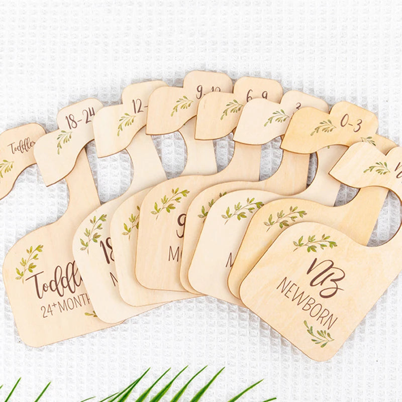 A set of wooden baby closet dividers with names and birth dates carved into the wood