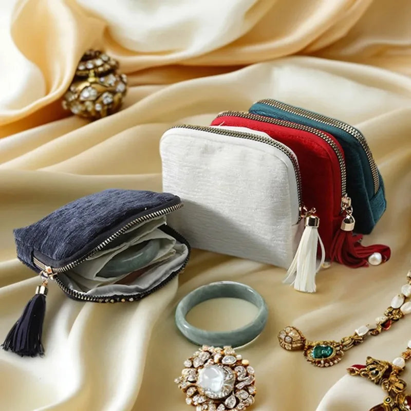 A collection of elegant velvet jewelry storage bags in various colors and textures, including a dark blue bag with tassels an