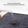A close-up shot of water dripping onto a dark gray microfiber towel.