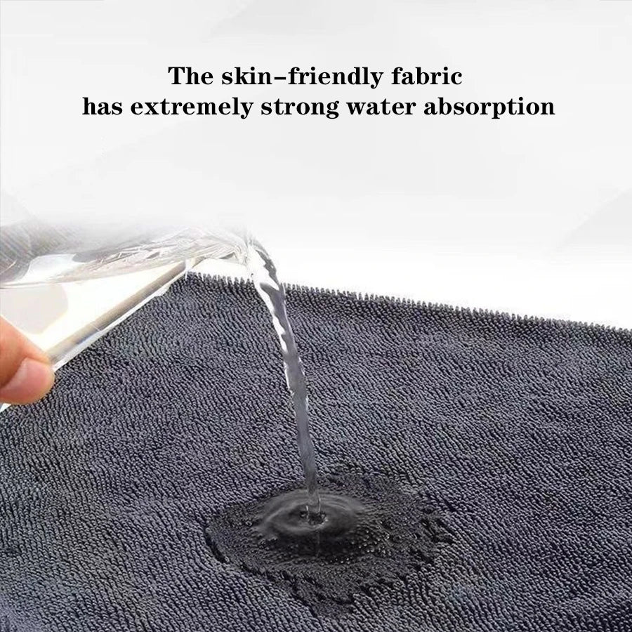 A close-up shot of water dripping onto a dark gray microfiber towel.