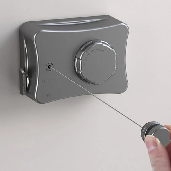 A gray retractable stainless steel clothesline mounted on a wall, showing the locking mechanism.