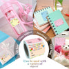 A collection of round self-adhesive gift tags in pink and yellow are shown alongside a glass bottle, notebook, and gift bag.