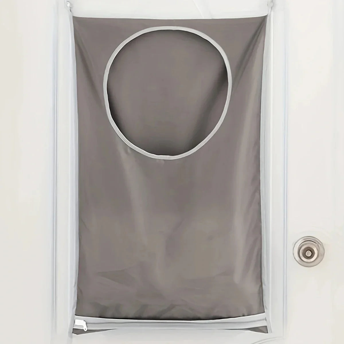 A gray fabric laundry organizer with a circular opening hanging on a white door.