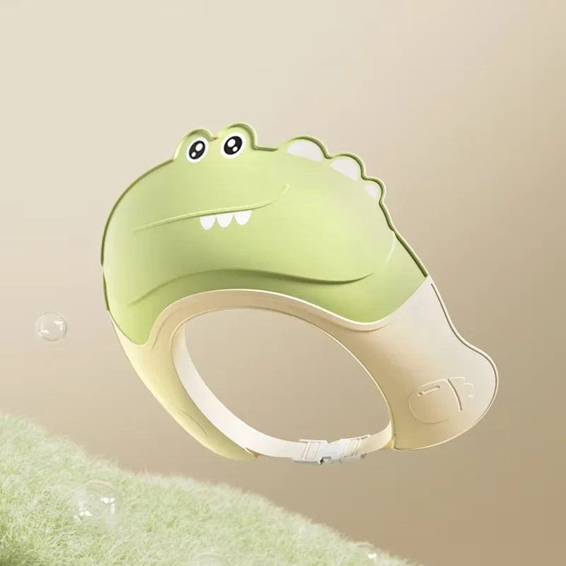 A light green adjustable baby bath shampoo shield cap is shown against a soft, blurred background.
