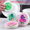 Ten pieces of random colored eco-friendly wood pulp sponges for kitchen cleaning displayed on a white plate.