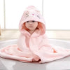 Baby in pink hooded towel and swaddle lying on a white surface.