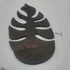 A dark brown wooden wall art frame shaped like a palm leaf, with small metal fasteners visible.