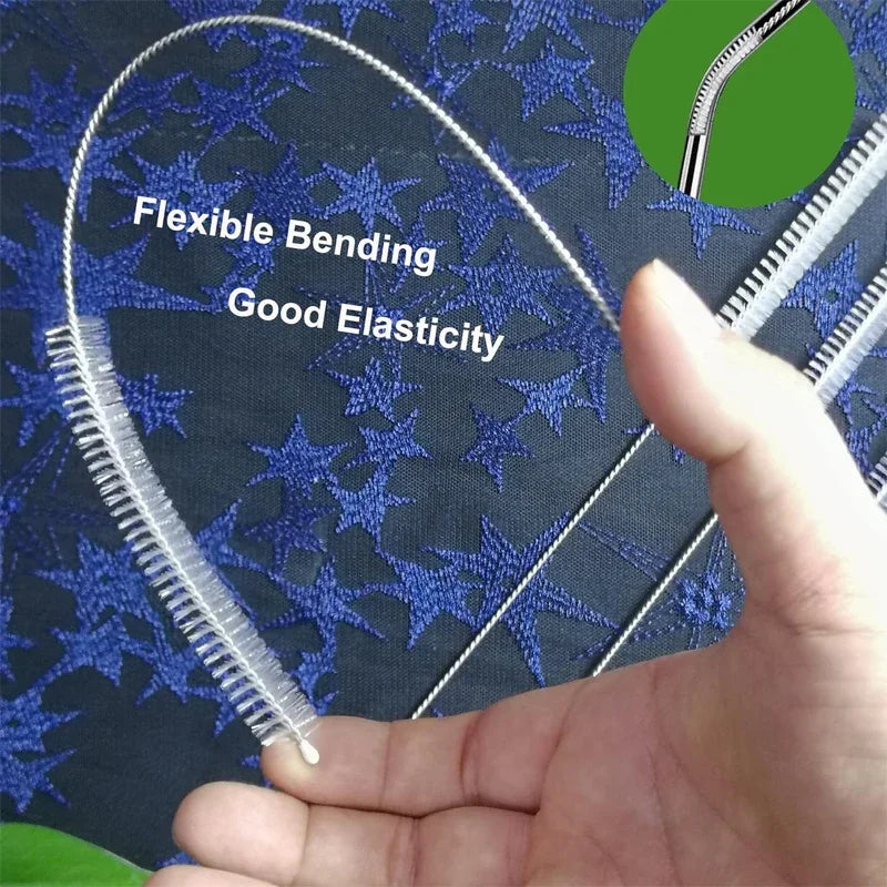 A hand holds a flexible stainless steel straw cleaning brush kit against a dark blue fabric background.