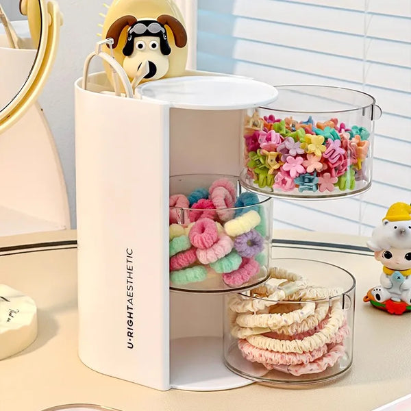 A white acrylic organizer holds various colorful hair accessories and makeup items, including a yellow bear charm.