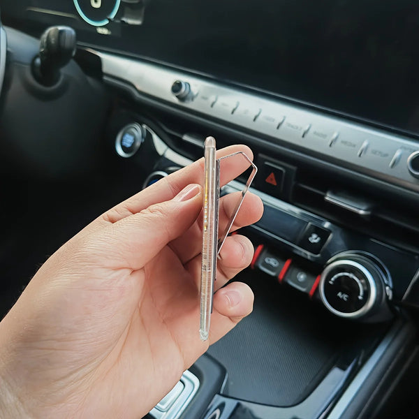 A hand holds a clear acrylic photo clip designed as a car sun visor accessory.