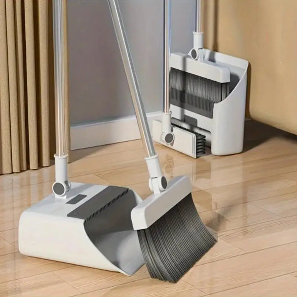 Set plegable de escoba y recogedor blanca con cepillo gris sobre un suelo de madera.