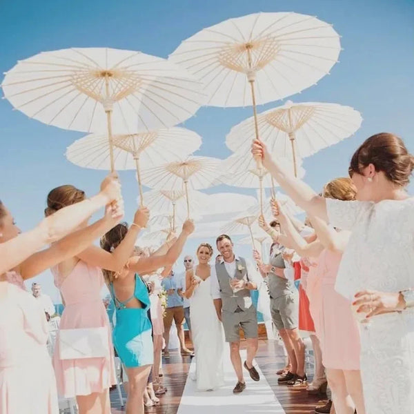 A group of people holding elegant white paper parasols outdoors during an event.