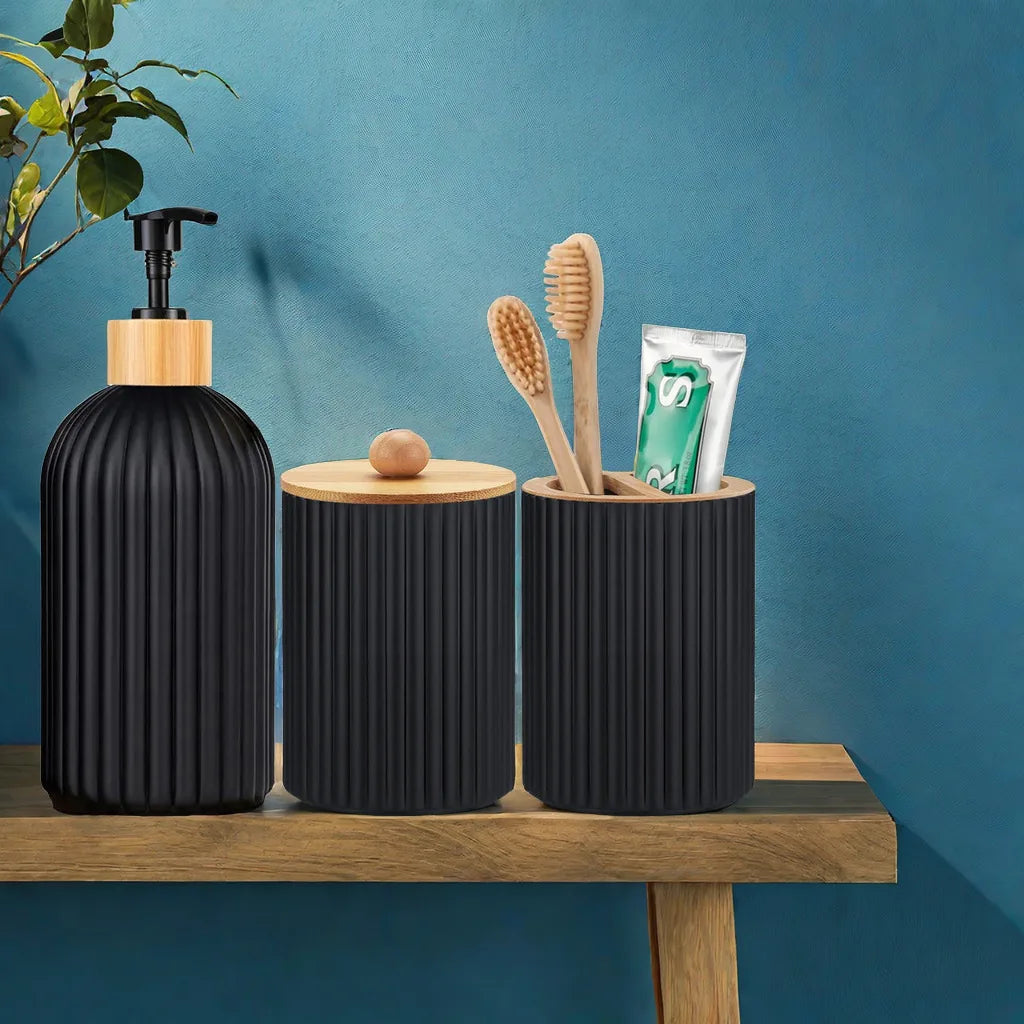 A black dispenser bottle and a cylindrical holder with wooden bristles and a soap bar on a wooden shelf.