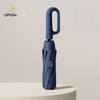 A dark blue windproof automatic folding umbrella standing upright on a light surface.
