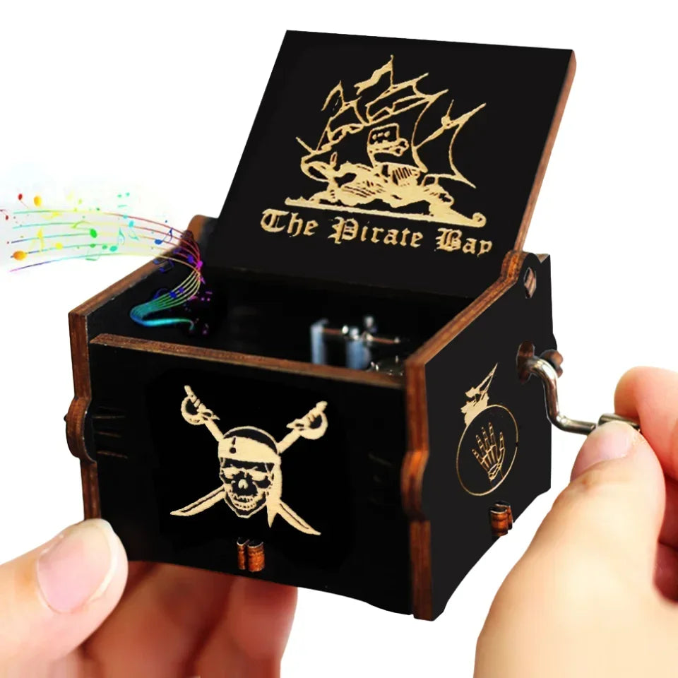 A dark wooden pirate-themed music box with a hand crank mechanism.
