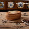 Handwoven rattan storage basket with lid shown on a wooden surface.