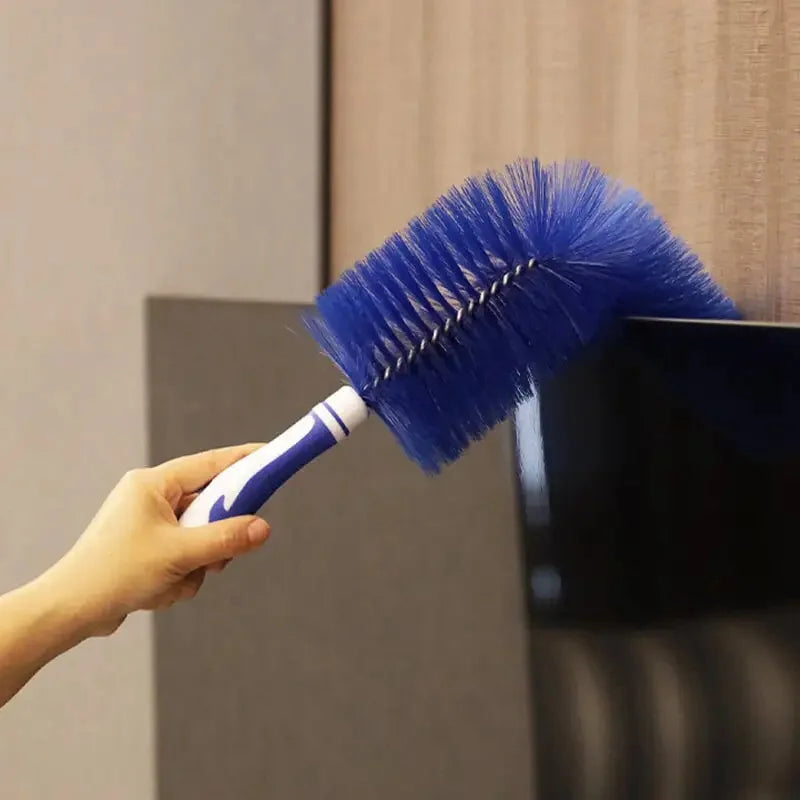 A hand holds a blue bendable fan brush for deep cleaning against a dark surface.