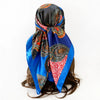 A vibrant blue silk scarf with an intricate paisley print tied around a dark hair
