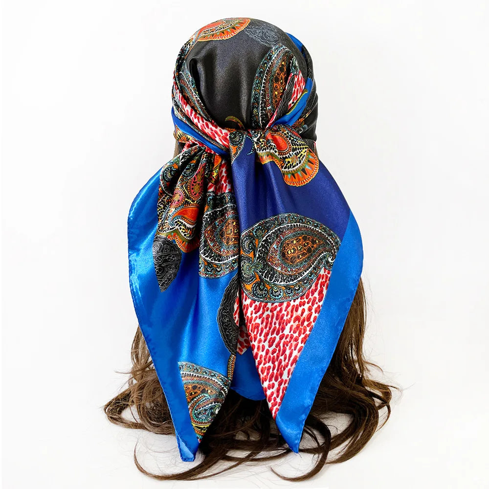 A vibrant blue silk scarf with an intricate paisley print tied around a dark hair