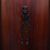 A dark bronze or metal sculpture of a full human skeleton, suitable for fridge magnets.