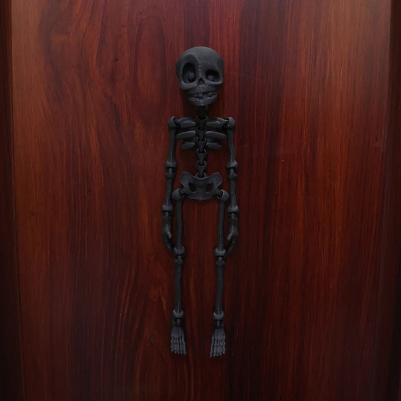 A dark bronze or metal sculpture of a full human skeleton, suitable for fridge magnets.