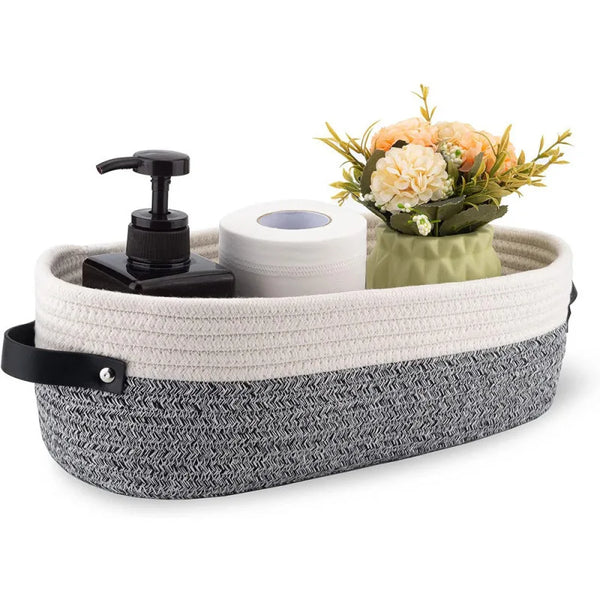 A woven cotton storage basket holding a roll of toilet paper and a bouquet of orange flowers.