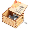Caja de música de madera manual con tapa que presenta un diseño de sol y un mecanismo metálico visible.