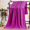 A stack of vibrant magenta microfiber bath towels draped over a black metal rack.