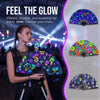 A woman holds a holographic gradient rave hand fan against a blurred background of a vibrant music event.