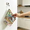 A hand is hanging a Totoro cartoon-themed fabric towel on a white wall hook.