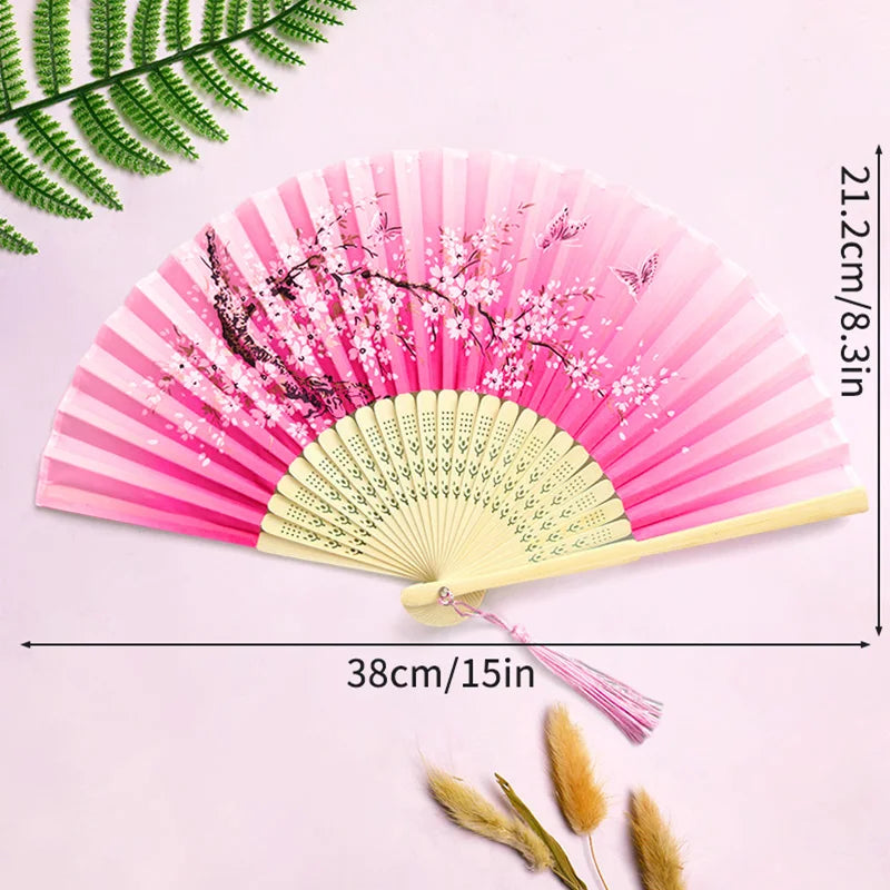 Pink and white lace fabric folding hand fan with pink blossoms on a light pink background