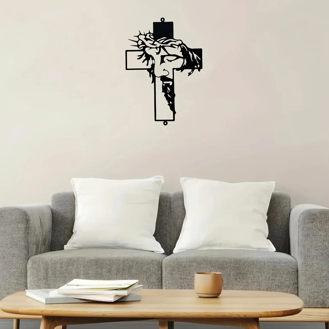 Black metal cross wall art featuring a carved face design displayed above a gray sofa.