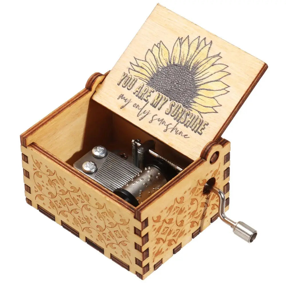 Caja de música de madera con mecanismo de manivela de latón y tapa con diseño de girasol.
