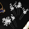 A set of delicate white pearl flower bridal hair clips with silver accents displayed on a black background.