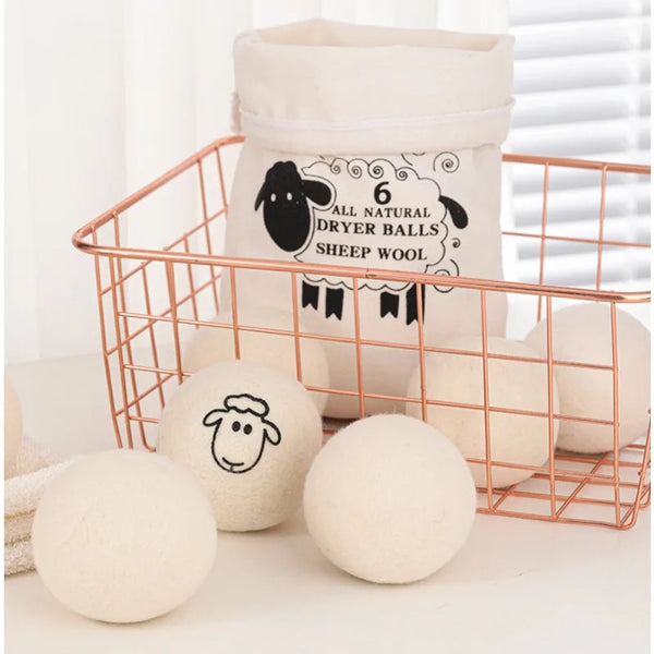 A set of six natural sheep wool dryer balls stored in a wire basket.