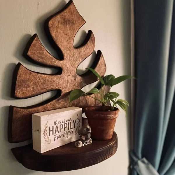 Un cadre d'art mural en bois en forme de feuille monté sur une étagère en bois foncé.