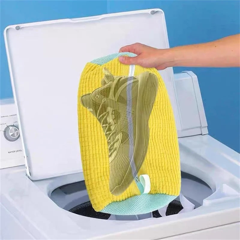 Una mano coloca una bolsa para lavar zapatillas anti-deformación en el tambor de una lavadora blanca.