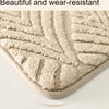 Close-up of a beige, textured, wear-resistant bathroom rug with a visible shadow on a white surface.
