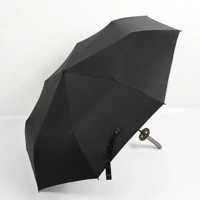 A black folding katana sword umbrella is shown open against a white background.